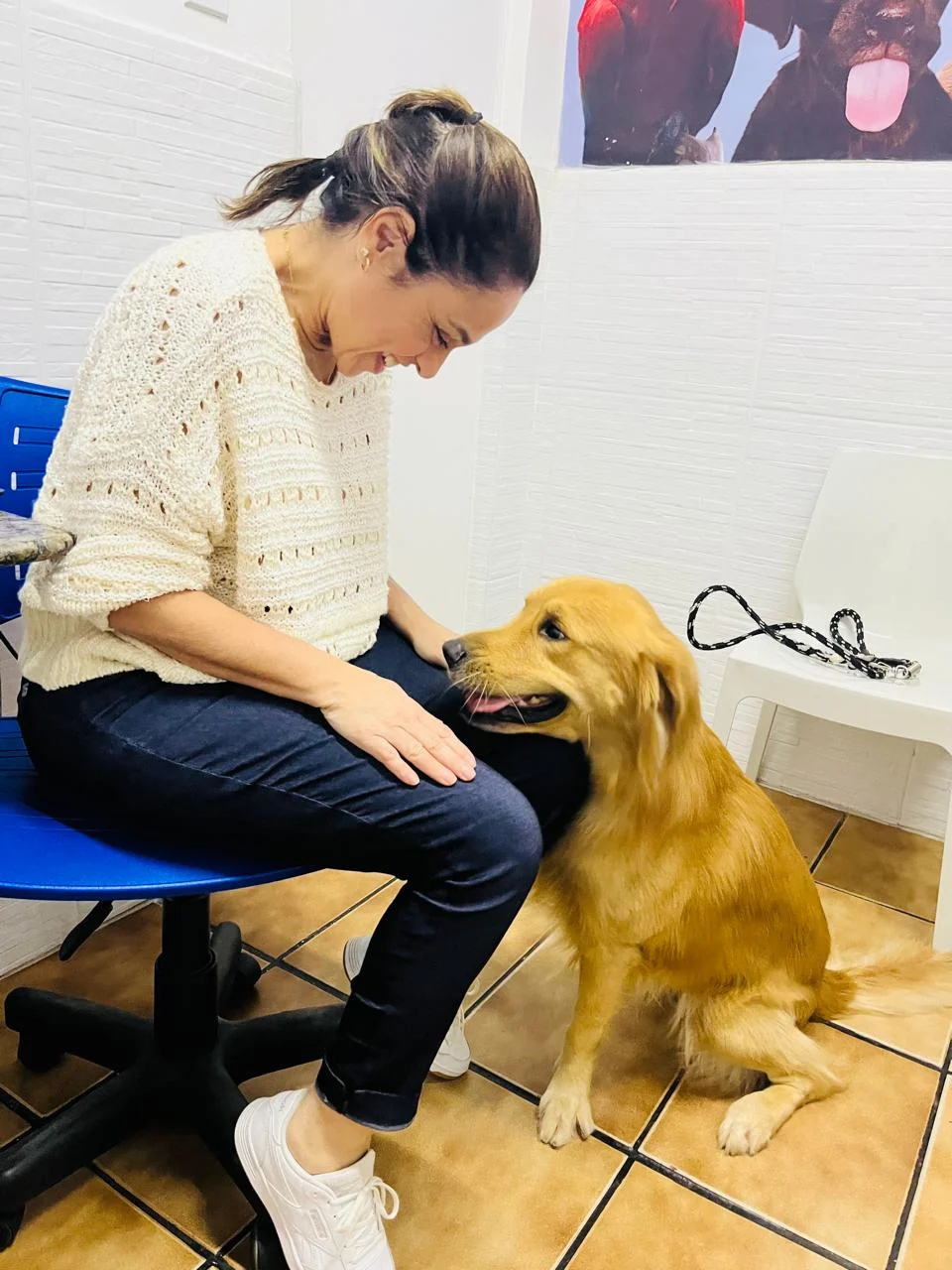 Dra. Caroline Keffer sentada, sorrindo para um golden retriever ao lado dela