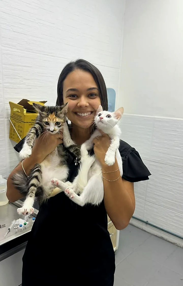 Colaboradora sorrindo com dois gatos no colo