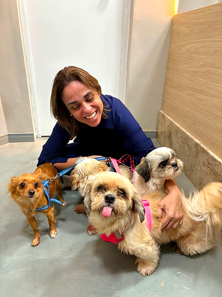 Dra. Caroline Keffer agachada no chão cercada por quatro cães pequenos
