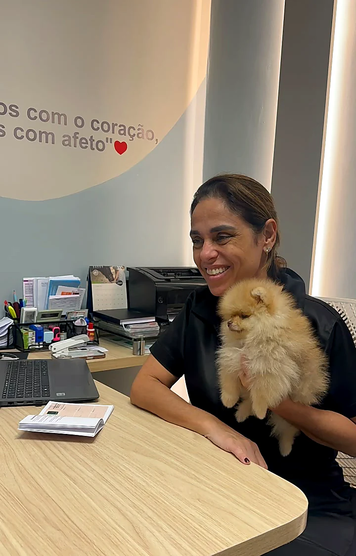 Colaboradora na mesa do consultório com um lulu da pomerânia
