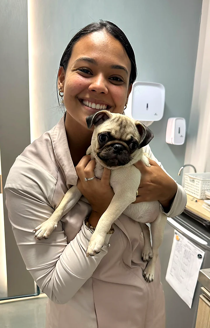 Colaboradora sorrindo com um pug no colo