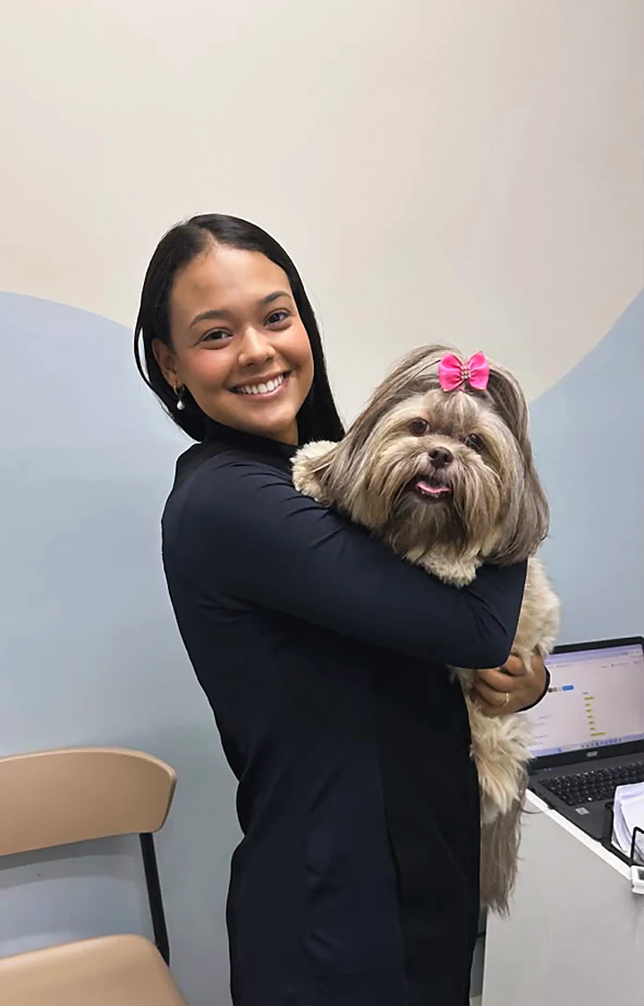 Colaboradora abraçando um shih-tzu de laço rosa